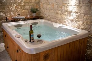 洛弗Apanemia Inn Studio的浴缸配有一瓶葡萄酒和玻璃