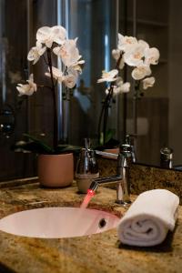 布达佩斯布达佩斯公寓酒店 的浴室柜台设有水槽和白色鲜花
