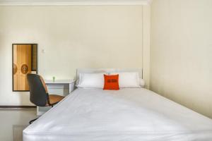 泗水KoolKost Syariah near Kaza Mall Surabaya的一张位于一个房间的床,上面有橙色枕头