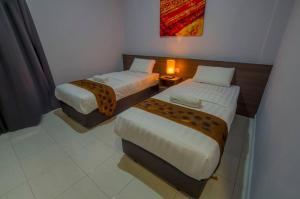 RembauHotel Seri Rembau的客房设有两张床和一张带台灯的桌子。