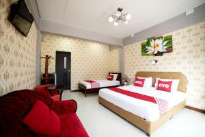 大城OYO 465 Krung Kao Traveller Lodge的酒店客房,配有两张床和椅子