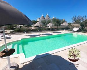 马丁纳弗兰卡Il Carpino的一座带遮阳伞的游泳池位于度假酒店旁