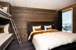 朗伊尔城Svalbard Hotell | Lodge的一间卧室设有一张大床和木墙