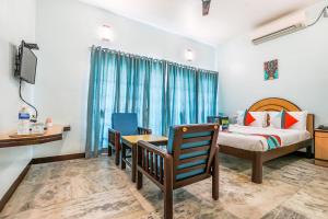 蓬蒂切里FabExpress Santhi Inn, Promenade Beach的一间卧室配有一张床、一张书桌和一台电视。