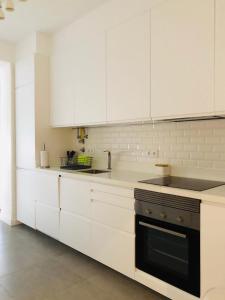 蒙蒂茹Apartamento espaçoso e confortável no centro do Montijo的白色的厨房配有白色橱柜和烤箱