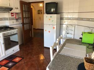 蒙丁-迪巴什图Casa do Rodrigo的厨房配有冰箱,餐桌上配有电视