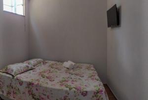 戈亚斯州上帕莱索KITNET'S DA DENI的一间卧室配有一张带花卉床单的床和一台电视。
