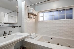 卡农海滩波浪酒店的白色的浴室设有浴缸和水槽。