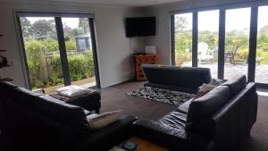 新普利茅斯Purakau Bed & Breakfast的客厅配有2张沙发和1台平面电视