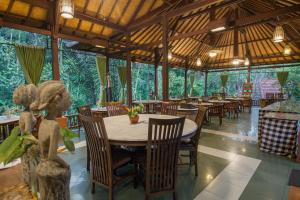 乌布Bali Spirit Hotel and Spa, Ubud的一间设有桌椅和树木的餐厅
