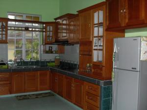KemasikFarah Banglo Homestay Kemasik的厨房配有木制橱柜和白色冰箱。