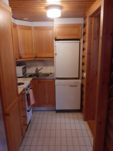 萨翁林纳Pankkotupa 66 "13B"的厨房配有木制橱柜和白色冰箱。