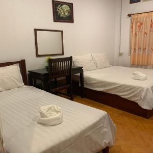 东德岛达洛姆旅馆的一间设有两张床、椅子和镜子的房间