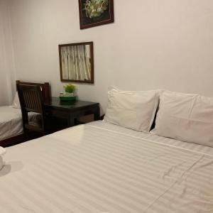东德岛达洛姆旅馆的一间卧室配有一张带白色床单的床和一张书桌。