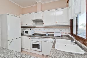 德尼亚Bahia Azul VyB的厨房配有白色橱柜和水槽