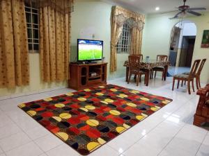 太平Muslim Homestay Ustaz 2的一间带电视和地毯的客厅