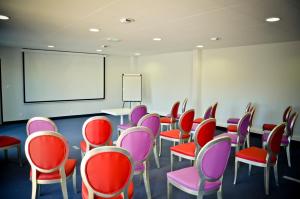 拉波勒拉波勒阿多尼斯酒店的一间教室,配有红色和紫色椅子和白色板