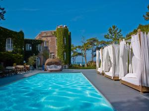 埃特勒塔圣克莱尔 - 第戎地区酒店的房屋前的带白色遮阳伞和椅子的游泳池