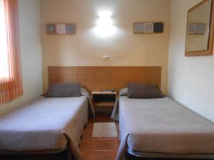 塔拉戈纳翼可乐杰旅馆的一间设有两张床和一张桌子的房间