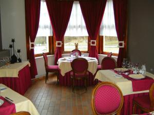 雅莱勒佩蒂特诺曼德酒店的一间配备有桌椅和红色窗帘的用餐室