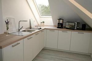 维尔德斯豪森Zuhause Woanders - Kuhtrade的厨房配有白色橱柜、水槽和窗户。