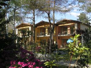 坎诺比奥Villaggio Turistico Riviera的前面有树木和鲜花的房子