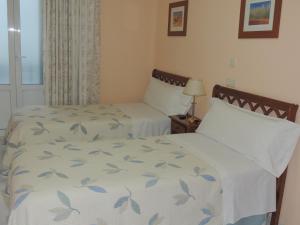 马德里冈萨洛旅馆的一间卧室设有两张床和窗户。