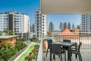 黄金海岸Rainbow Bay Resort Holiday Apartments的阳台配有桌椅和建筑