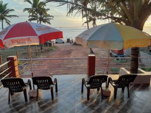 瓦斯科达伽马Leon Hide Out Guest House的海滩上的两把遮阳伞和椅子