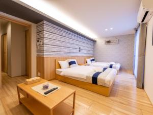 广岛GRAND BASE Hiroshima Hikarimachi的酒店客房设有两张床和一张桌子。