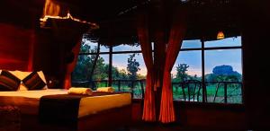 锡吉里亚Chena Huts Eco Resort的一间卧室设有一张床和一个大窗户