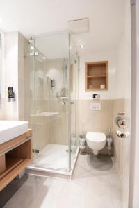 胡苏姆Nordsee-Hotel Hinrichsen的一间带玻璃淋浴和卫生间的浴室