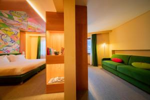 奥斯塔OMAMA Hotel的酒店客房,设有一张床铺和一张绿色沙发