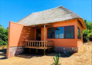 BiserukaKikonko Lodge的一座带茅草屋顶的橙色小房子