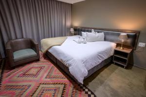 布隆方丹Sangiro Game Lodge的配有一张床和一把椅子的酒店客房