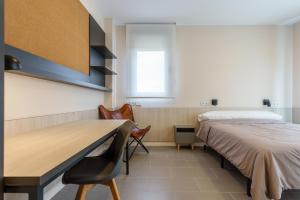 马拉加Residencia Universitaria Campus Málaga的一间卧室设有两张床、一张桌子和一个窗口。