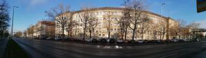 柏林Hostel VITA Berlin的一座大型建筑,前面有汽车停放