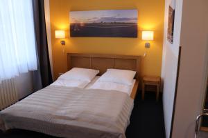 柏林Hostel VITA Berlin的一间卧室配有两张带白色床单和绘画的床