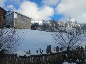DanisparauliGuest House Luka的一座带栅栏和建筑物的雪覆盖的院子