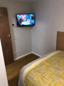 诺丁汉228 Cinderhill Road的卧室配有一张床和壁挂式平面电视。