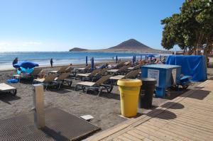 厄尔梅达诺APARTAMENTOS LOS LAURELES的海滩上设有躺椅和椅子,还有大海