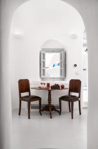 伊亚Oia Spirit Boutique Residences的餐桌、两把椅子和镜子