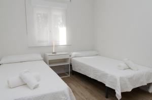 马德里Moderno,tranquilo, entrada autónoma y fácil aparcamiento.的白色的客房设有两张床和窗户。