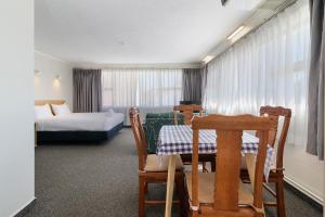 罗托鲁瓦Thermal Oak Motel的酒店客房带一张床、一张桌子和椅子