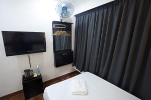 古晋美音酒店 - 古晋海滨店的酒店客房带一张床、一台电视、一张床和一台电视机。
