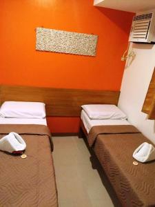 马尼拉帕塞石屋酒店的橙色墙壁的客房内的两张床