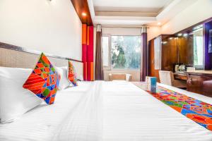 新德里FabHotel Marble Arch的一间卧室配有一张带色彩缤纷枕头的大床