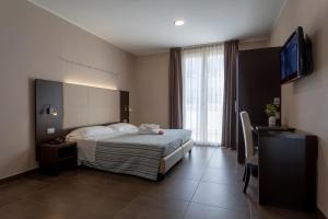 里米尼格米酒店的一间卧室配有一张床和一台平面电视