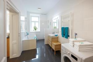 维也纳施塔特哈勒 - 家庭城市公寓的白色的浴室设有洗衣机和水槽。