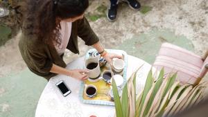 贝加德圣马特奥Camino Art House的把咖啡杯托盘放在桌子上的女人